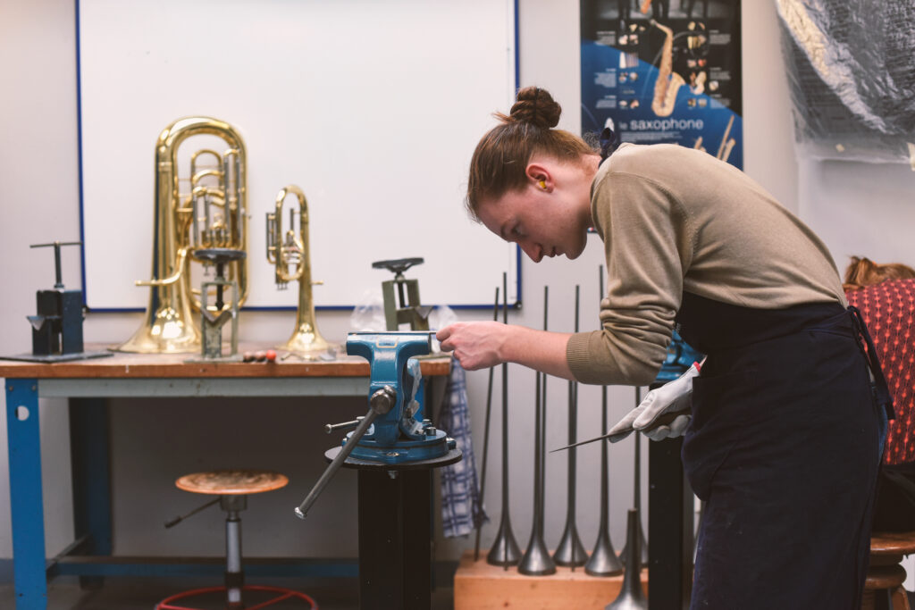 Un homme travaille sur une pièce de métal dans l'atelier lutherie instruments vents de l'Itemm, l'école basée au Mans qui forme les professionnels de la lutherie.